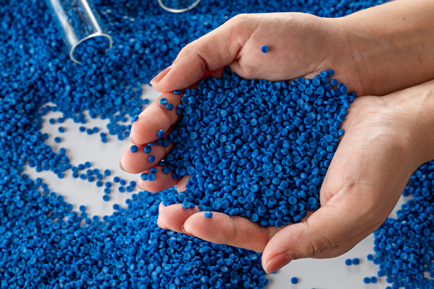 A person holds a handful of small blue plastic circles