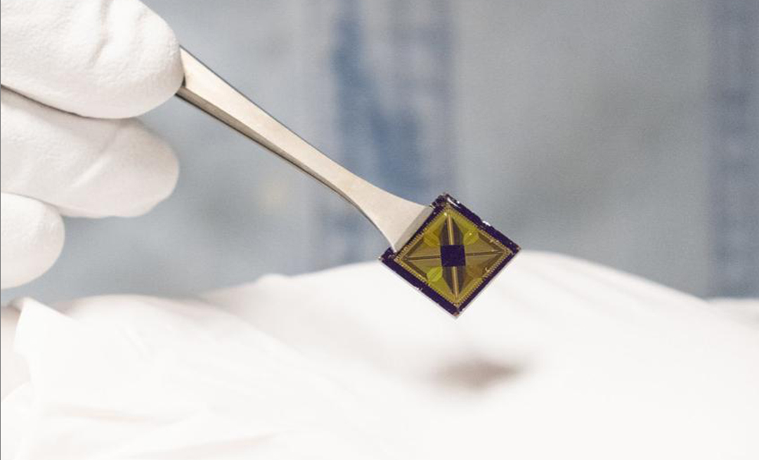 An up-close shot of a small chip held by tweezers
