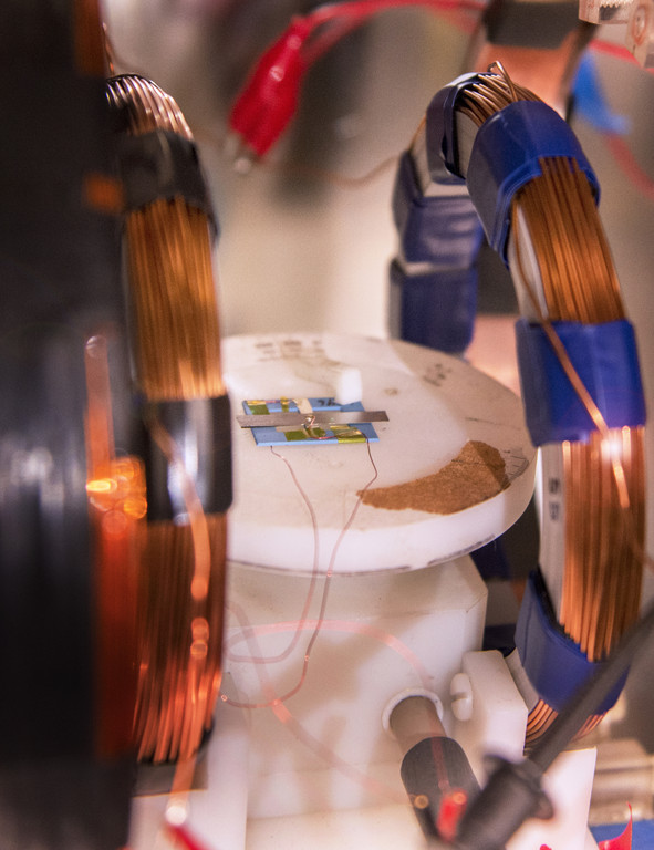 Helmholtz coils made of copper wire apply a magnetic field to a small magnetoelectric magnetometer to calibrate it. The magnetometer senses magnetic fields; this one is designed to detect the fields generated by neurons in the brain.