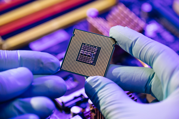 A gloved hand holds a microchip